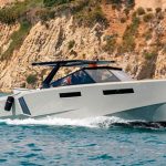 Modern motorboat cruising near rocky coastline
