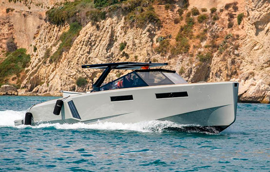 Modern motorboat cruising near rocky coastline